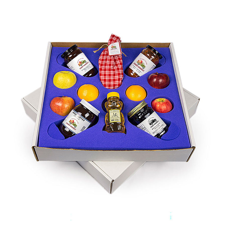 Gift set with jars, apples, and oranges in a box on a white background.