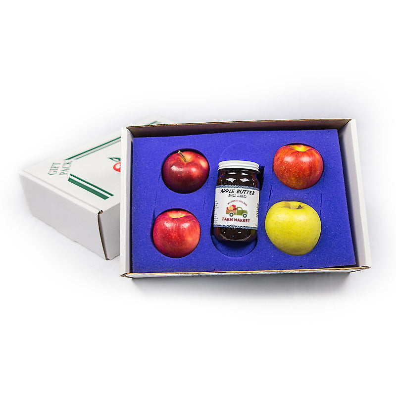 Box with apple butter jar and red and yellow apples on a white background