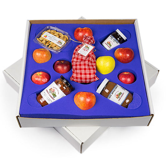 Gourmet gift set with apples, jam, and nuts in a box on a white background.